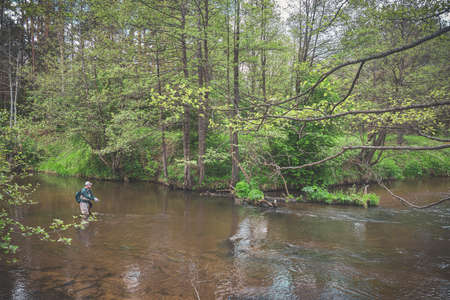 The fisherman catches with a spinning rod on the river.の写真素材