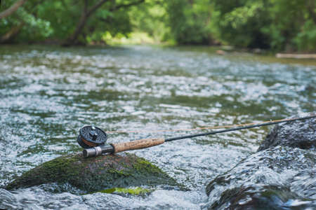 The fly rod lies on the rocks against the backdrop of a mountain stream.の写真素材