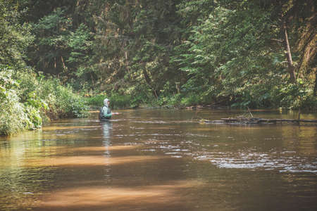 A fisherman catches grayling and trout on a forest stream.の写真素材