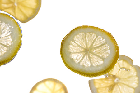 Slices of lemon drifting in water, white studio backgroundの写真素材