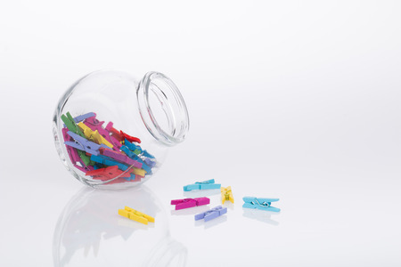 Glass jar of colorful miniature clothespins on white backgroundの写真素材