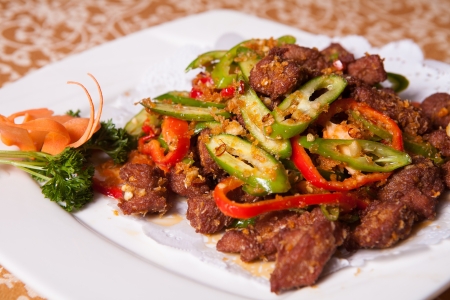 fried beef and green peppers on a white plateの写真素材