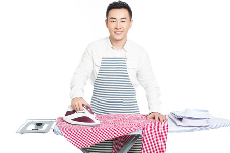 young man ironing his clothes isolated against white backgroundの写真素材