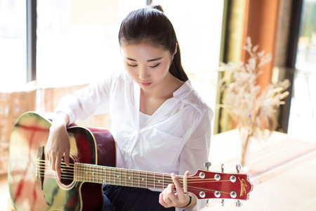chinese black hair girl playing acoustic guitarの写真素材