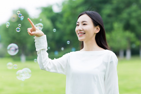 young brunette girl blowing soap bubbles at outdoor.の写真素材