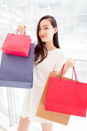 asian girl, carrying her shopping bags, showing her shopping achievementの写真素材