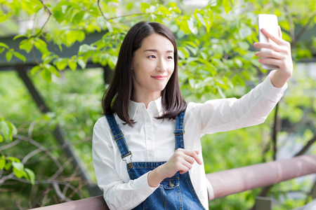 chinese girl taking self portrait in the parkの写真素材