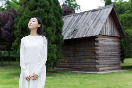 young chinese woman standing alone in front of the Cabin villageの写真素材