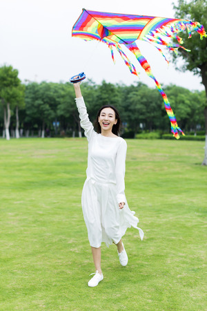 asian girl holding a kite in the park ready to flyの写真素材
