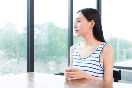 close up portrait of lady holding a glass of drinking waterの写真素材