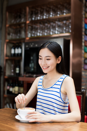 Young lady drinking a cup of coffee in a cafeの写真素材