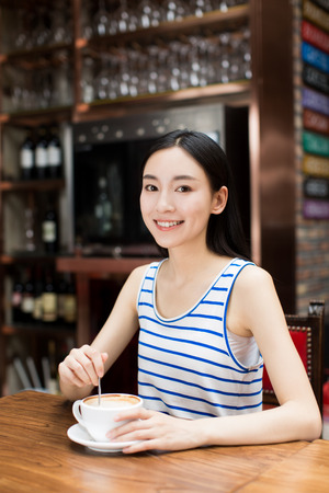 Young lady drinking a cup of coffee in a cafeの写真素材