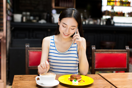 young woman talking on the phone at a coffee shop.の写真素材