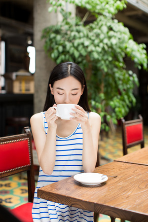 woman drinking a cup of coffee and smilingの写真素材