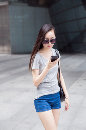 fashion chinese girl carrying a black bag walking in a shopping centerの写真素材