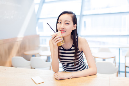 chinese pretty girl sitting alone in a coffee shopの写真素材