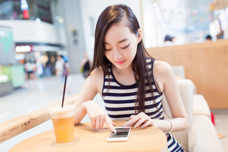 chinese girl sitting alone in a coffee shopの写真素材