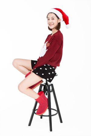 Young woman wearing santa hat sitting on stool.の写真素材