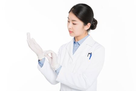 Young woman in surgical gown putting on medical glovesの写真素材
