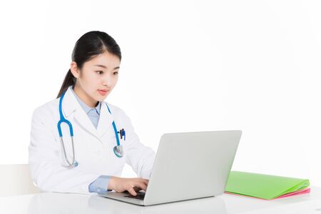 Female doctor in surgical gown working on laptopの写真素材