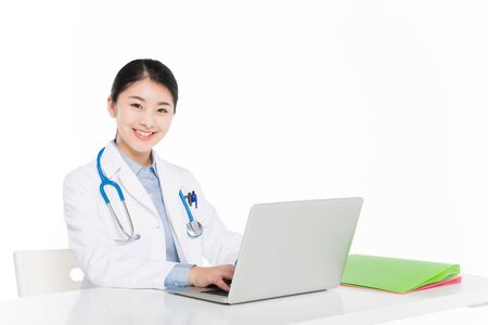 Female doctor in surgical gown working on laptopの写真素材