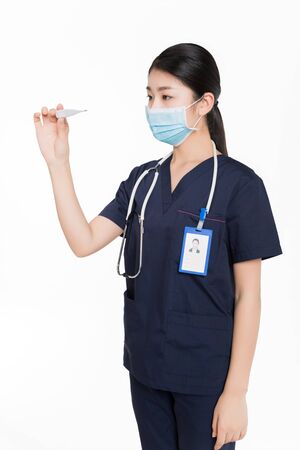 Female surgeon with surgical mask looking at a thermometerの写真素材