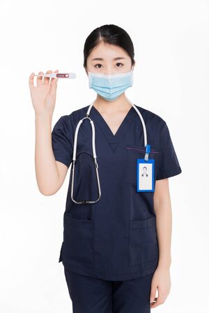 Female surgeon with surgical mask showing a thermometerの写真素材