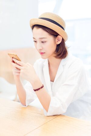 beautiful woman texting messages in a cafe of shooping center,shandong province,china.の写真素材