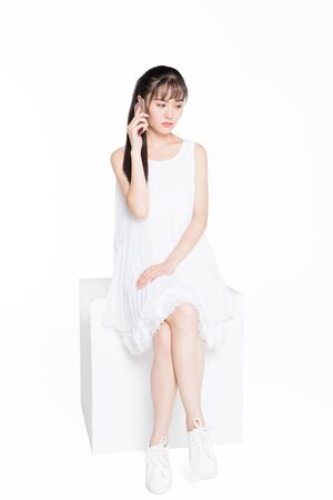 a young woman with bad mood talking on phone,studio shot.の写真素材