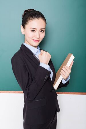 portrait of female teacher pointing to chalkboard, chinese, asia.の写真素材