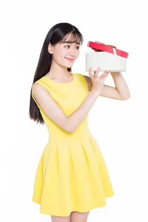Beautiful teenage girl in yellow skirt is holding gift boxの写真素材