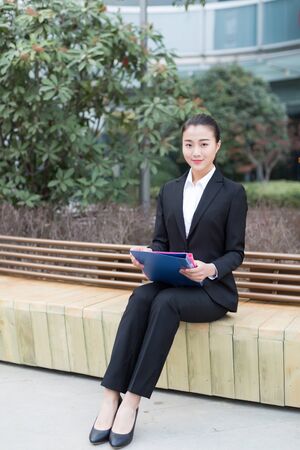 young female secretary wearing a black suit holding a folderの写真素材
