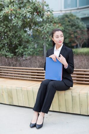 young female secretary wearing a black suit holding a folderの写真素材