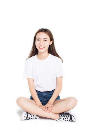 beautiful girl sitting on the ground over white background.の写真素材
