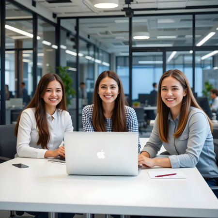 Portrait of smiling businesswomen using laptop at desk in creative officeの素材