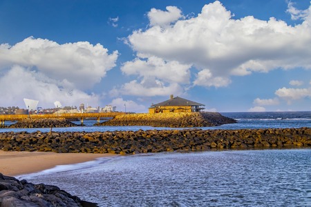Beautiful sunset on the beach with red volcanic sand. There is a small hat over the water, Caleta de...