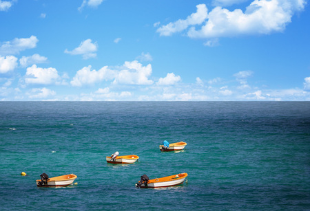 Exotic beautiful marine beach with small boats on blue water of sea and sky with white clouds. It is situated in Fuerteventura, Canary island.の写真素材