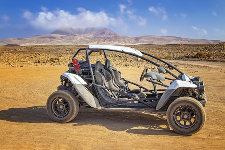 White buggy in stone and sandy desert on volcanic island Fuerteventura, Canary islands, Spain. In the background is blue sky.の写真素材