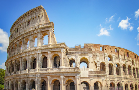 The Colosseum is in Roma, Italy. It is a large stone ruin. There is sunny day in summer. Blue sky is...