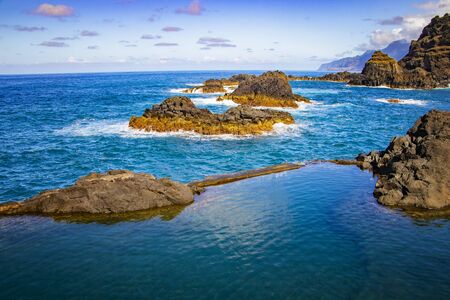 Swimming natural pools of volcanic lava in Seixal, Madeira island, Portugal, Europe. There is beautiful view on sea cliffs and waves of Atlantic ocean. There is summer time.の写真素材