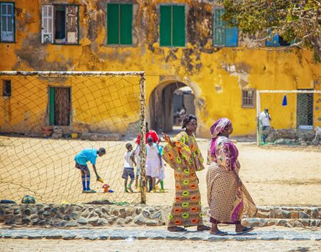 Goree, Senegal, APRIL 22, 2019: Unidentifed Senegal women are wearing the typical colorful traditional Senegalese clothes. Women walk and children playing football there. It is summer time.のeditorial素材