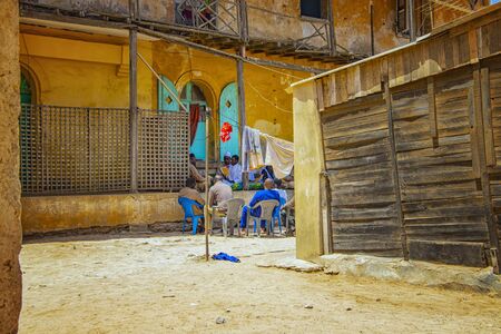 GOREE/SENEGAL - April 22, 2019: A group of senegalese men sitting and chatting on a dusty street at...