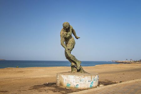 Stone statue of a runner standing on the seashore of Dakar, Senegal, Africa. It is a beautiful long...