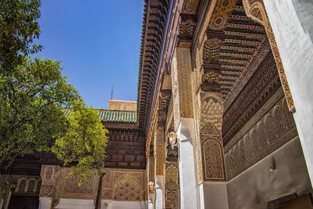 Detail of islamic building. It is an old architecture in the middle of the Moroccan city. There are white walls with wooden carved characters. There is summer time. It's a beautiful pattern.の写真素材