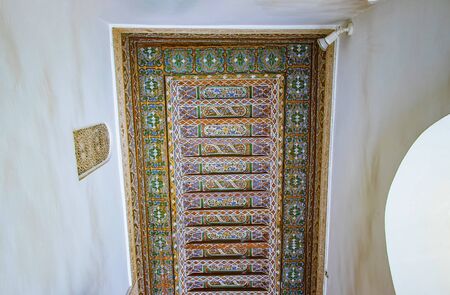 Detail of islamic building. It is an old architecture in the middle of the Moroccan city. There are white walls with wooden carved characters. There is summer time. It's a beautiful pattern.の写真素材