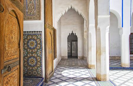 Detail of islamic building. It is an old architecture in the middle of the Moroccan city. There are white walls with wooden carved characters. There is summer time. It's a beautiful pattern.の写真素材