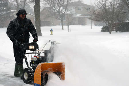 Man snow blowing driveway after heavy snowfallの写真素材