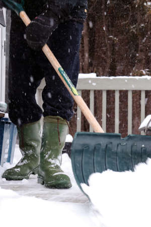 Man shoveling deck in the snow after storm.の写真素材