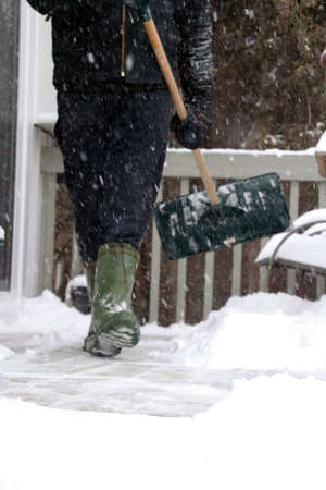 Man shoveling snowy steps after blizzardの写真素材