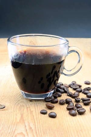 Cup of black coffee on wood surface with whole roasted coffee beansの写真素材